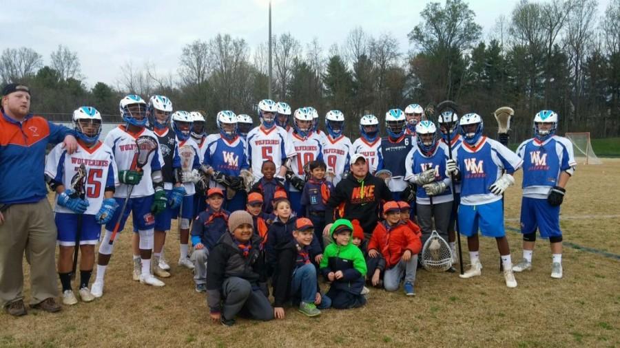 El equipo universitario masculino lacrosse posa con el entrenador Jordan Montesano y los Boy Scouts locales