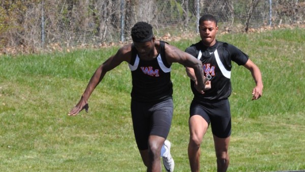 Senior Gedeon Elenga taking a handoff from junior Nathaniel Vault in a relay race. 