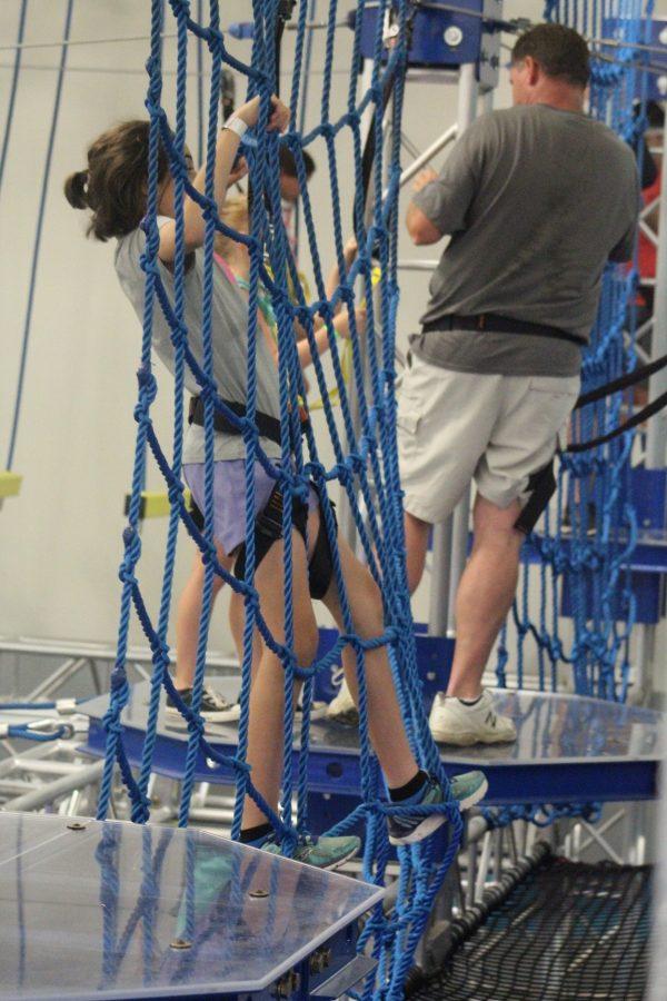 A young girl climbing cargo nets on the High Ropes Course