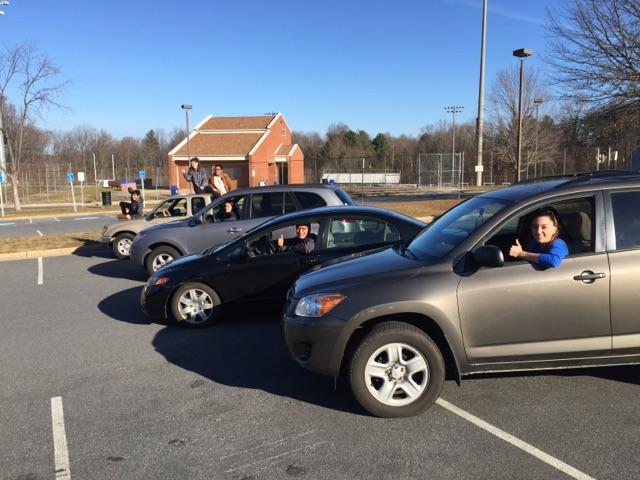 Seniors pose with their cars in the student parking lot