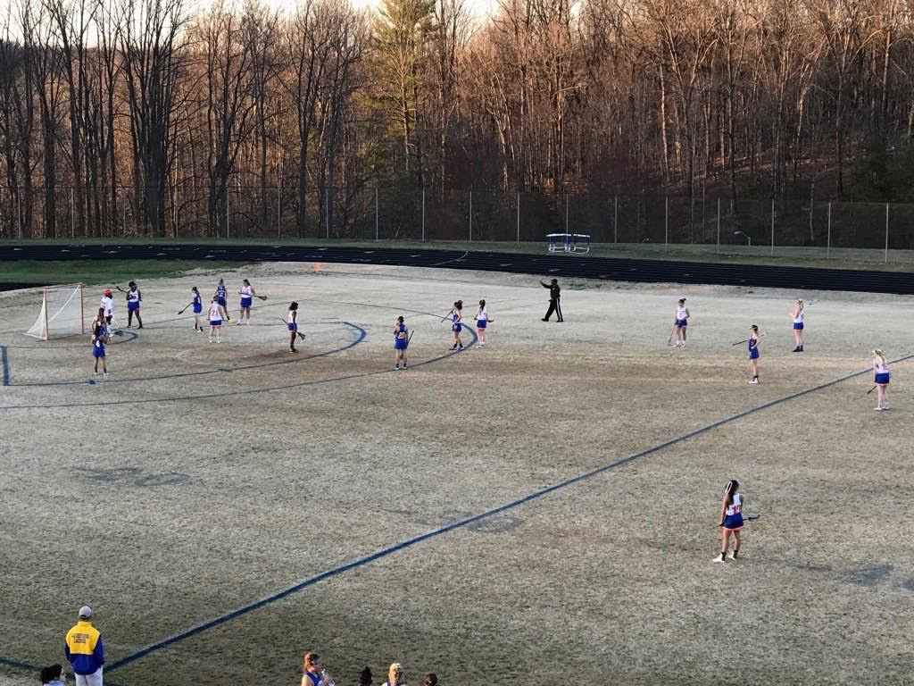 Girls lacrosse in the middle of their game. 
