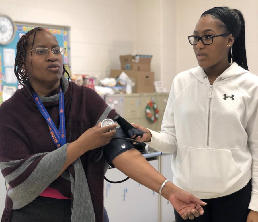 Medical careers teacher Paula Mascendaro demonstrates proper blood pressure technique to senior Taylor Johnson.  Students were not permitted to take pictures on the field trip to protect patient privacy.