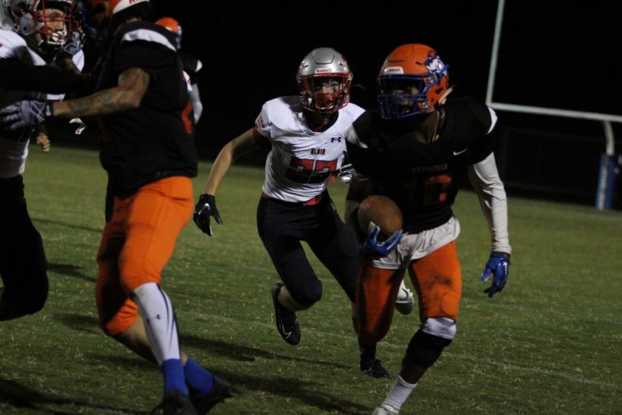 Junior Darnell Lewis Jr. runs the ball down the field, moving past a Blair football player.