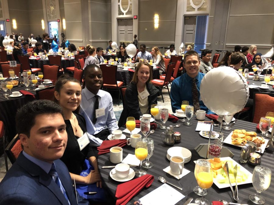 Los estudiantes del último año Richard Epperly, Adaly Ascencio, Francis Eseh y Nadia Makmak se sientan con el maestro de recursos científicos Matt Reese en el desayuno de los superintendentes.