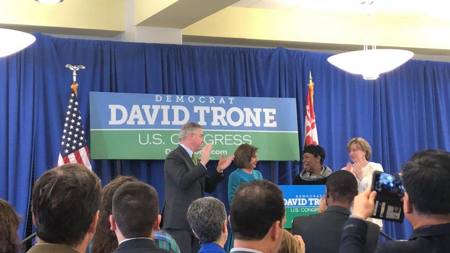 David Trone, Nancy Pelosi, and Adrienne Jones  greeting each other on stage. 